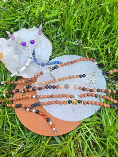 Bijoux artisanaux en perles, disposés sur une surface avec une pierre précieuse, sur herbe.