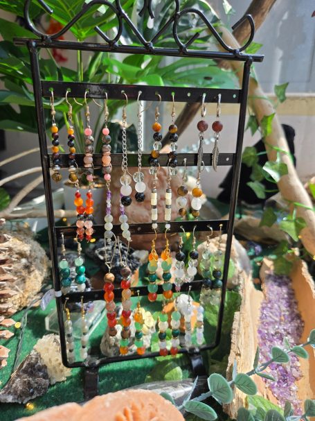 Présentoir en fer avec des boucles d'oreilles colorées et des accessoires en pierres.